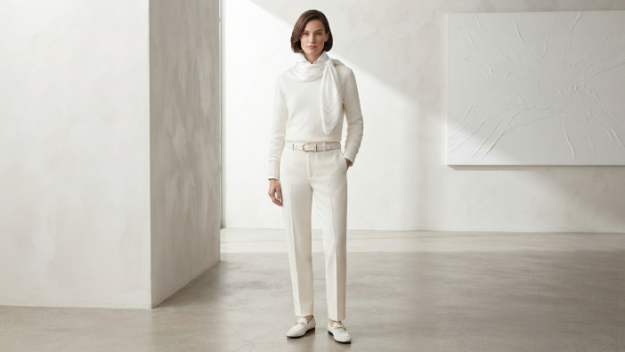 Person wearing an all-white monochrome outfit in a bright minimalist setting